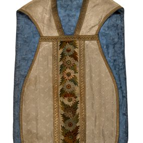 Zdjęcie nr 1: Boki ornatu z białej tkaniny wiskozowej, żakardowej. Wzór o kompozycji rzędowej z motywem trzech nachodzących na siebie okręgów, zwróconych w prawo lub w lewo i przesuniętymi o połowę szerokości raportu w kolejnych rzędach.
Tylna preteksta z tkaniny półjedwabnej o splocie atłasowym, lansowanej nićmi o oplocie metalowym gładkim i karbowanym oraz nićmi bawełnianymi o splocie rządkowym, całość zabezpieczona ściegiem łańcuszkowym. Kompozycja złożona z dwóch przeplatających się wici; złota ze stylizowanymi strzępiastymi liśćmi i wolutowo wygiętymi witkami, żółto-zielona z liśćmi i owocami winnego krzewu. Na przecięciu ramion krzyża preteksty medalion z wizerunkiem Matki Boskiej Apokaliptycznej. Przednia preteksta haftowana na kanwie ściegiem liczonym nićmi bawełnianymi i wełną; na białym tle główki kwiatów w otoczeniu strzępiastych liści, ułożone wertykalnie, w zimnych odcieniach zieleni, brązu i szarości. 
Galony tkane z nićmi o oplocie miedzianym w wątku, w dwóch szerokościach, z motywem zygzaka, jeden lub dwa brzegi ząbkowane.
Podszewka z tkaniny wiskozowej, żakardowej, w kolorze niebieskim. Wzór o kompozycji pasowej z motywem geometrycznym oraz dwóch rodzajów gałązek z kwiatami  i listkami, zwróconymi w prawo lub w lewo i przesuniętymi o połowę szerokości raportu w kolejnych pasach.
