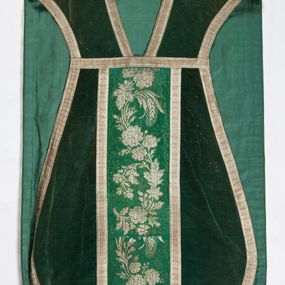 Zdjęcie nr 1: Boki ornatu z zielonego aksamitu bawełnianego.
Preteksty z zielono-srebrnej borty liturgicznej, z jedwabno-bawełnianej, lansowanej nicią o oplocie srebrnym, miejscami wprowadzone bawełniane wątki lansujące w kolorze brązowym, tło z subornamentem o motywach roślinnych. Wzór z motywem esowato wygiętej wici z kwiatów róży, drobnych polnych kwiatów i kłosów zboża. Na przecięciu ramion krzyża tylnej preteksty litery IHS z krzyżem łacińskim otoczone koroną cierniową. Tło przeszyte ściegiem maszynowym w sposób nieregularny.
Galon tkany z nićmi o oplocie miedzianym srebrzonym w wątku i lamelką wzdłuż osnowy w kolorze srebrnym, brzegi z ząbkami.
Podszewka z tkaniny bawełnianej o splocie rządkowym, w kolorze zielonym.
