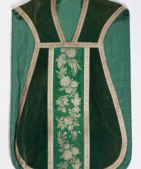 Zdjęcie nr 1: Boki ornatu z zielonego aksamitu bawełnianego.
Preteksty z zielono-srebrnej borty liturgicznej, z jedwabno-bawełnianej, lansowanej nicią o oplocie srebrnym, miejscami wprowadzone bawełniane wątki lansujące w kolorze brązowym, tło z subornamentem o motywach roślinnych. Wzór z motywem esowato wygiętej wici z kwiatów róży, drobnych polnych kwiatów i kłosów zboża. Na przecięciu ramion krzyża tylnej preteksty litery IHS z krzyżem łacińskim otoczone koroną cierniową. Tło przeszyte ściegiem maszynowym w sposób nieregularny.
Galon tkany z nićmi o oplocie miedzianym srebrzonym w wątku i lamelką wzdłuż osnowy w kolorze srebrnym, brzegi z ząbkami.
Podszewka z tkaniny bawełnianej o splocie rządkowym, w kolorze zielonym.
