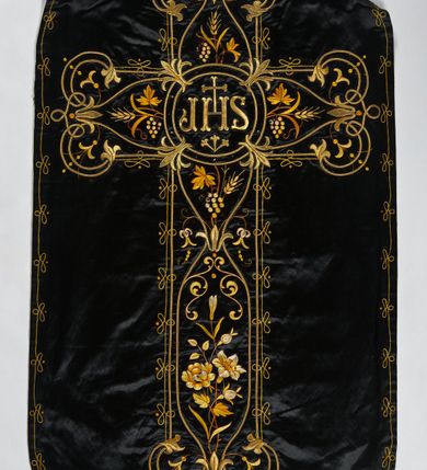 Zdjęcie nr 2: Ornat z czarnej tkaniny półjedwabnej o splocie atłasowym.

Preteksty wyznaczone haftem barwnym, ściegiem łańcuszkowym maszynowym nićmi sztucznymi, uzupełnione haftem kładzionym z sutaszem o oplocie miedzianym złoconym oraz haftem na podkładzie tekturowym nićmi gładkimi i karbowanymi o oplocie miedzianym złoconym. Kompozycja roślinno-kwiatowa zamknięta pomiędzy dwoma wiciami fantazyjnie wygiętymi na zakończeniach, z motywami lilii andegaweńskich, w kolorze złotym oraz gałązek winnej latorośli z gronami, kłosami zboża i gałązkami kwiatu róży i lilii, w odcieniach brązu. Na przecięciu ramion tylnej preteksty litery IHS z krzyżem łacińskim i gwoźdźmi, w kolorze złotym. Całość otacza dekoracyjny fryz w kolorze żółtym.

Podszewka z tkaniny bawełnianej o splocie rządkowym, w kolorze czarnym. Na podszewce metka w kolorze białym, z jasnoniebieskim napisem: "Made in France/The C. Wildermann Co/NEW - YORK".