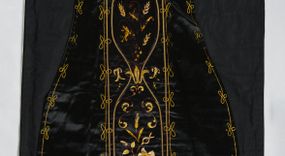 Zdjęcie nr 1: Ornat z czarnej tkaniny półjedwabnej o splocie atłasowym.

Preteksty wyznaczone haftem barwnym, ściegiem łańcuszkowym maszynowym nićmi sztucznymi, uzupełnione haftem kładzionym z sutaszem o oplocie miedzianym złoconym oraz haftem na podkładzie tekturowym nićmi gładkimi i karbowanymi o oplocie miedzianym złoconym. Kompozycja roślinno-kwiatowa zamknięta pomiędzy dwoma wiciami fantazyjnie wygiętymi na zakończeniach, z motywami lilii andegaweńskich, w kolorze złotym oraz gałązek winnej latorośli z gronami, kłosami zboża i gałązkami kwiatu róży i lilii, w odcieniach brązu. Na przecięciu ramion tylnej preteksty litery IHS z krzyżem łacińskim i gwoźdźmi, w kolorze złotym. Całość otacza dekoracyjny fryz w kolorze żółtym.

Podszewka z tkaniny bawełnianej o splocie rządkowym, w kolorze czarnym. Na podszewce metka w kolorze białym, z jasnoniebieskim napisem: "Made in France/The C. Wildermann Co/NEW - YORK".