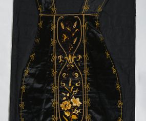 Zdjęcie nr 1: Ornat z czarnej tkaniny półjedwabnej o splocie atłasowym.

Preteksty wyznaczone haftem barwnym, ściegiem łańcuszkowym maszynowym nićmi sztucznymi, uzupełnione haftem kładzionym z sutaszem o oplocie miedzianym złoconym oraz haftem na podkładzie tekturowym nićmi gładkimi i karbowanymi o oplocie miedzianym złoconym. Kompozycja roślinno-kwiatowa zamknięta pomiędzy dwoma wiciami fantazyjnie wygiętymi na zakończeniach, z motywami lilii andegaweńskich, w kolorze złotym oraz gałązek winnej latorośli z gronami, kłosami zboża i gałązkami kwiatu róży i lilii, w odcieniach brązu. Na przecięciu ramion tylnej preteksty litery IHS z krzyżem łacińskim i gwoźdźmi, w kolorze złotym. Całość otacza dekoracyjny fryz w kolorze żółtym.

Podszewka z tkaniny bawełnianej o splocie rządkowym, w kolorze czarnym. Na podszewce metka w kolorze białym, z jasnoniebieskim napisem: "Made in France/The C. Wildermann Co/NEW - YORK".