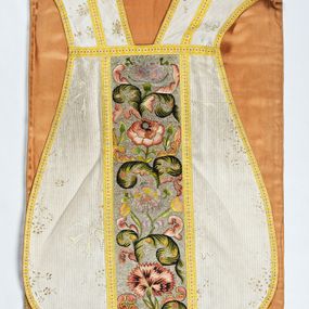 Zdjęcie nr 1: Boki ornatu z białej tkaniny wiskozowej o splocie rypsowym z malowanym wzorem z motywów okazałych bukietów drobnych kwiatów przewiązanych kokardą i mniejszych gałązek kwiatowych. W górnej części ornatu, na wysokości ramion, tkanina wiskozowa o tle w splocie rypsowym, żakardowa, z wzorem o kompozycji pasowej z ułożonych poziomo bukiecików drobnych kwiatków z listkami i luźno rozrzuconych małych kwiatków.

Preteksty w partii tła założone haftem kładzionym nicią o oplocie metalowym w kolorze srebrnym; wzór haftowany barwnymi nićmi ściegiem cieniowanym,  z motywem gałązek z fantazyjnie wygiętymi liśćmi i barwnymi kwiatami, m.in. róży i goździka. Dolna część tylnej preteksty uzupełniona podobnym haftem.

Galony tkane z nici sztucznych, trójbarwne (tło żółte, wzór biało-czerwony), w dwóch szerokościach i o dwóch wzorach: 1. przy pretekstach szerszy, z motywem białych krzyżyków greckich, motywem w kształcie litery X i rombów z wpisanym małym krzyżykiem, wszystkie z czerwonymi środkami; 2. na brzegach, z motywem białych krzyżyków greckich i ośmiopłatkowych kwiatków, z czerwonymi środkami i przedzielone czerwonymi kostkami. U dołu przedniej preteksty wstawiony fragment galonu tkanego z nićmi o oplocie miedzianym srebrzonym w wątku, z motywem falistej prążkowanej wstęgi i trójklapowych listków.

Podszewka z tkaniny wiskozowej o splocie rządkowym, w kolorze pomarańczowym.