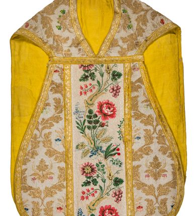 Zdjęcie nr 1: Boki ornatu z tkaniny jedwabnej, o tle atłasowym lansowanej nićmi o oplocie metalowym w kolorze złotym oraz nićmi jedwabnymi wielobarwnymi. Wzór o kompozycji sieciowej, wyznaczony przez faliste, wznoszące się ku górze wici z bujnych liści, wyznaczające pola, w których dwa rodzaje symetrycznych kompozycji z kwiatów, liści i traw.

Preteksty z tafty w kolorze białym, pokrytej ściegiem łańcuszkowym. Wzór o splotach rządkowych, lansowany barwnymi nićmi jedwabnymi i nićmi o oplocie metalowym w kolorze złotym. Wzór z motywem falistej wici roślinnej z polnymi kwiatami, kłosami zbóż oraz kiściami winogron.

Galon tkany z nićmi o oplocie metalowym w wątku, w kolorze złotym, z motywem falistej wici roślinnej z liśćmi.

Podszewka z tkaniny bawełnianej, adamaszkowej, w kolorze żółtym, z motywem zygzaka przeplatającego się z wicią roślinną.