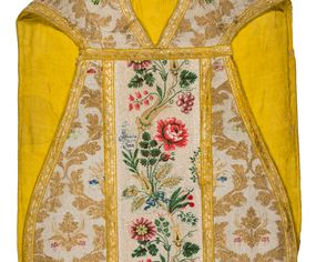 Zdjęcie nr 1: Boki ornatu z tkaniny jedwabnej, o tle atłasowym lansowanej nićmi o oplocie metalowym w kolorze złotym oraz nićmi jedwabnymi wielobarwnymi. Wzór o kompozycji sieciowej, wyznaczony przez faliste, wznoszące się ku górze wici z bujnych liści, wyznaczające pola, w których dwa rodzaje symetrycznych kompozycji z kwiatów, liści i traw.

Preteksty z tafty w kolorze białym, pokrytej ściegiem łańcuszkowym. Wzór o splotach rządkowych, lansowany barwnymi nićmi jedwabnymi i nićmi o oplocie metalowym w kolorze złotym. Wzór z motywem falistej wici roślinnej z polnymi kwiatami, kłosami zbóż oraz kiściami winogron.

Galon tkany z nićmi o oplocie metalowym w wątku, w kolorze złotym, z motywem falistej wici roślinnej z liśćmi.

Podszewka z tkaniny bawełnianej, adamaszkowej, w kolorze żółtym, z motywem zygzaka przeplatającego się z wicią roślinną.