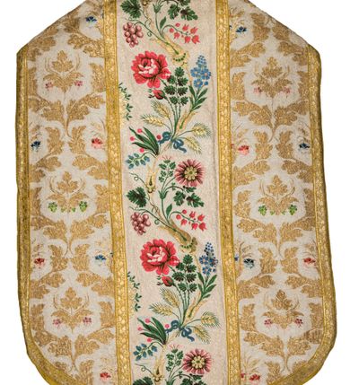 Zdjęcie nr 3: Boki ornatu z tkaniny jedwabnej, o tle atłasowym lansowanej nićmi o oplocie metalowym w kolorze złotym oraz nićmi jedwabnymi wielobarwnymi. Wzór o kompozycji sieciowej, wyznaczony przez faliste, wznoszące się ku górze wici z bujnych liści, wyznaczające pola, w których dwa rodzaje symetrycznych kompozycji z kwiatów, liści i traw.

Preteksty z tafty w kolorze białym, pokrytej ściegiem łańcuszkowym. Wzór o splotach rządkowych, lansowany barwnymi nićmi jedwabnymi i nićmi o oplocie metalowym w kolorze złotym. Wzór z motywem falistej wici roślinnej z polnymi kwiatami, kłosami zbóż oraz kiściami winogron.

Galon tkany z nićmi o oplocie metalowym w wątku, w kolorze złotym, z motywem falistej wici roślinnej z liśćmi.

Podszewka z tkaniny bawełnianej, adamaszkowej, w kolorze żółtym, z motywem zygzaka przeplatającego się z wicią roślinną.